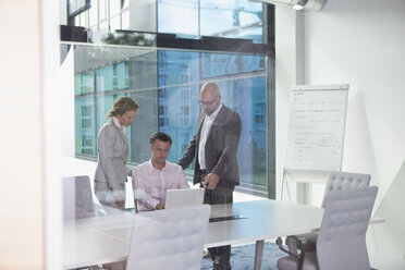 Three businesspeople with laptop in conference room - RBF002163