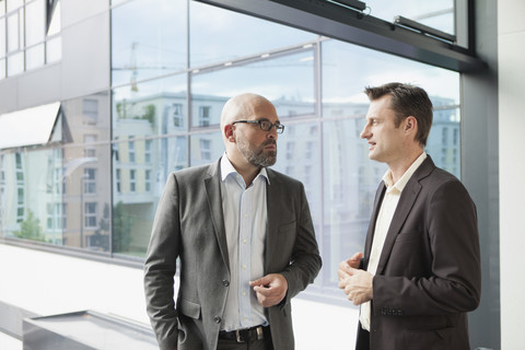 Zwei Geschäftsleute unterhalten sich im Büro, lizenzfreies Stockfoto