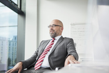 Selbstbewusster Geschäftsmann im Büro mit Blick aus dem Fenster - RBF002178