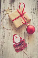Weihnachtsgeschenk mit roter Christbaumkugel und Weihnachtsmann auf Holz - SARF001148