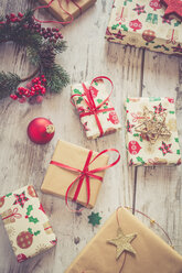 Eingepackte Weihnachtsgeschenke und rote Christbaumkugel auf Holz - SARF001150