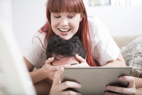 Couple lying in bed woman covering man's eyes with her hands - ZEF002921