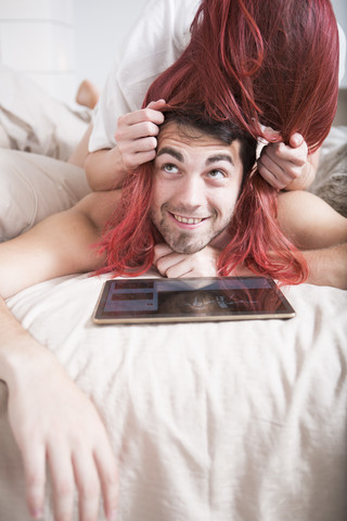 Paar im Bett liegend Frau bedeckt den Kopf des Mannes mit ihrem Haar, lizenzfreies Stockfoto