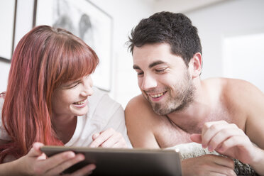 Young couple lying in bed using digital tablet - ZEF002928