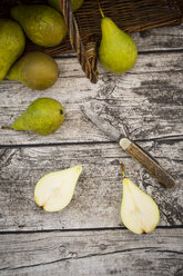 Whole and sliced organic pears and a pocket knife on grey wood - LVF002468