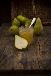 Whole and sliced organic pears and glass of pear jam on dark wood - LVF002473