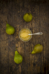 Four organic pears and glass of pear jam on dark wood - LVF002475