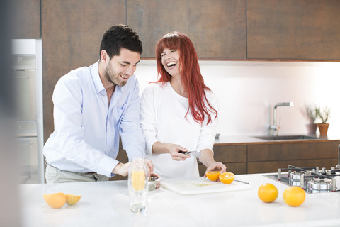 Ehepaar in der Küche bei der Herstellung von frischem Orangensaft, lizenzfreies Stockfoto
