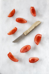 Slices of pitted tomato and a kitchen knife on white marble - EVGF001041