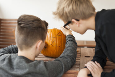 Zwei Jungen bereiten einen Kürbis für eine Halloween-Laterne vor - PAF001097