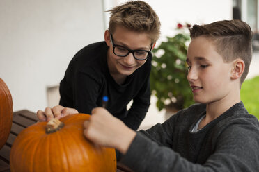 Zwei Jungen bereiten einen Kürbis für eine Halloween-Laterne vor - PAF001098