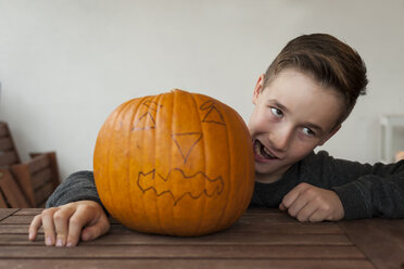 Junge, der neben einem großen Halloween-Kürbis ein Gesicht macht - PAF001099