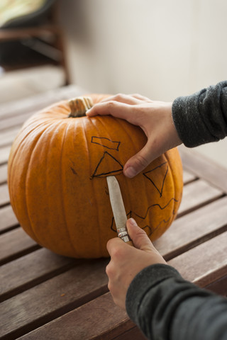 Boy's hands preparing a pumpkin for Halloween lantern stock photo