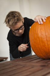 Junge bereitet einen übergroßen Kürbis für eine Halloween-Laterne vor - PAF001101