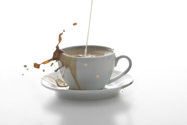 Milch spritzt in eine Tasse Kaffee vor weißem Hintergrund - YFF000280