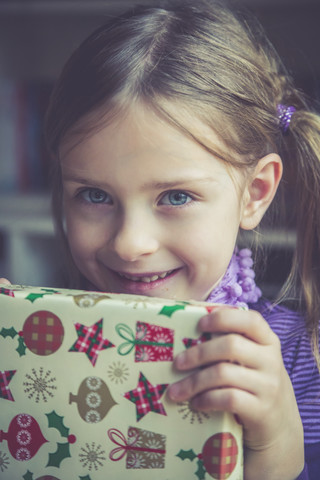 Porträt eines lächelnden kleinen Mädchens mit Weihnachtsgeschenk, lizenzfreies Stockfoto