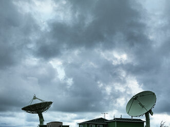 USA, Hawaii, Ka Lae, satellite dishes in front of cloudy sky - STKF001103