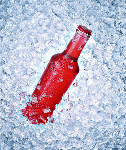 Glass bottle with red beverage on crushed ice stock photo