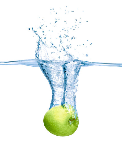 Green apple falling into water stock photo