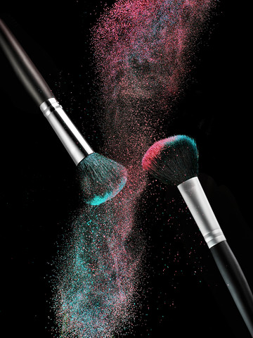 Coloured make-up powder and two beauty brushes in front of black background stock photo