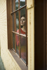Junge Frau schaut aus dem Fenster - UUF002875