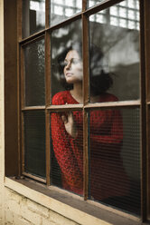 Junge Frau schaut aus dem Fenster - UUF002879