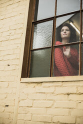 Junge Frau schaut aus dem Fenster - UUF002880