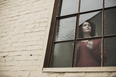 Junge Frau schaut aus dem Fenster - UUF002881