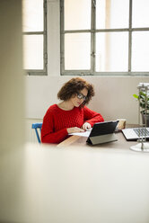 Young woman reading document at table - UUF002892