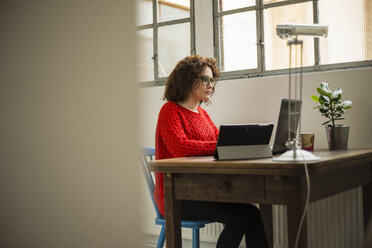 Junge Frau mit Laptop am Tisch - UUF002894