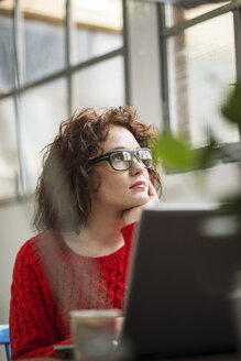 Young woman at desk thinking - UUF002904