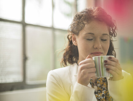 Junge Geschäftsfrau genießt eine Tasse Kaffee - UUF002910