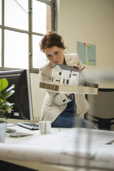 Junge Frau im Büro mit Architekturmodell - UUF002923