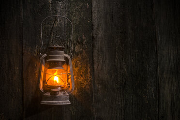 Beleuchtete alte Gaslaterne, die an einer Holzwand hängt - DEGF000070