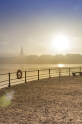 Germany, Hamburg, silhouette of town hall looming through the dense fog over the Alster lake - NKF000217