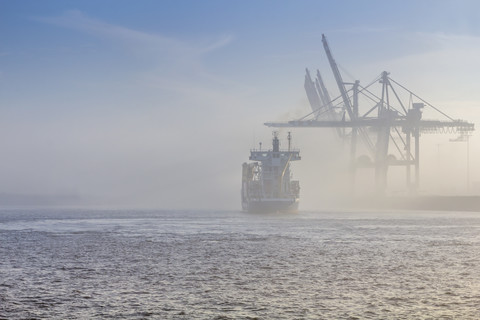 Deutschland, Hamburg, Containerschiff verschwindet im dichten Nebel im Hafen von Hamburg, lizenzfreies Stockfoto