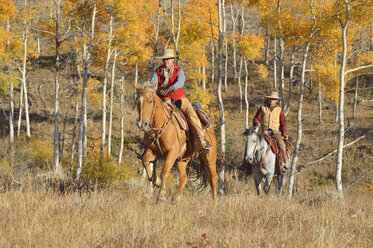 USA, Wyoming, Big Horn Mountains, reitendes Cowgirl und Cowboy im Herbst - RUEF001325
