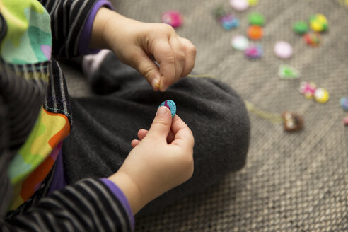 Girl playing with hand made buttons - MIDF000011