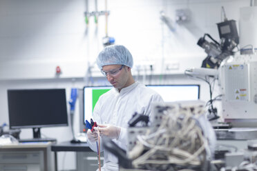 Technician in cleanroom holding cable - SGF001232