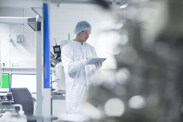 Technician in cleanroom holding digital tablet - SGF001233