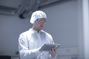 Technician in cleanroom holding digital tablet - SGF001234