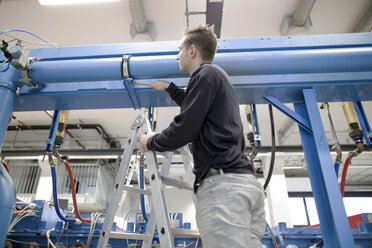 Junger Techniker prüft ein Rohr in einer Industriehalle - SGF001278