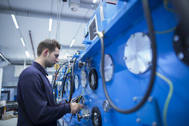 Junger Techniker bei der Kontrolle der elektrischen Energie in einer Industriehalle - SGF001282