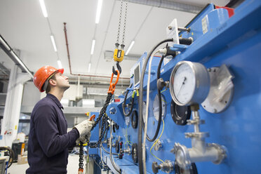 Junger Techniker am Haken eines Bohrturms in einer Industriehalle - SGF001283