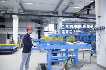 Junger Techniker bei der Arbeit in einer Industriehalle - SGF001284