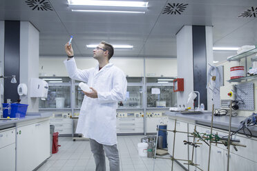 Chemikerin arbeitet im Labor und betrachtet ein Reagenzglas - SGF001241