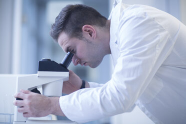 Wissenschaftlerin im Labor beim Blick durch ein Lichtmikroskop - SGF001248
