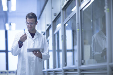 Chemist working in lab examining test tube - SGF001249