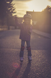 Little girl balancing on rollerblades at backlight - SARF001167