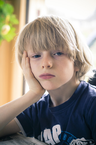 Porträt eines gelangweilten kleinen Jungen mit dem Kopf in der Hand, lizenzfreies Stockfoto